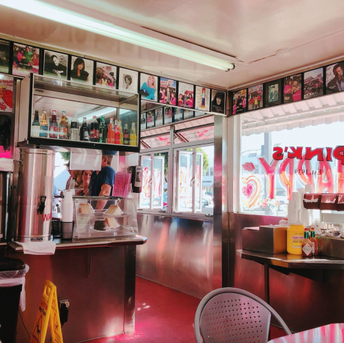 Interior of a vibrant diner with colorful photos on the walls, a counter with drinks, and a bright atmosphere.