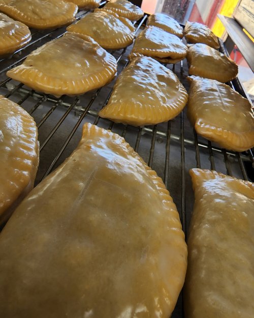 Freshly baked golden empanadas cooling on a wire rack.