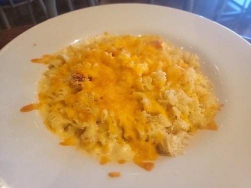 A creamy pasta dish topped with melted cheese, served in a white bowl.