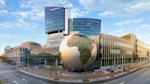 A modern building with a large globe sculpture of Africa in front, set against a clear sky.