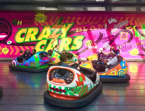 Colorful bumper cars in an amusement park, with excited riders and a vibrant, graffiti-style backdrop.