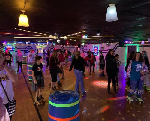 A lively roller skating rink filled with people skating under colorful lights and decorations.