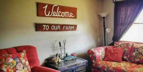 Cozy living room with floral sofas, a wooden coffee table, and a "Welcome to Our Farm" sign on the wall.