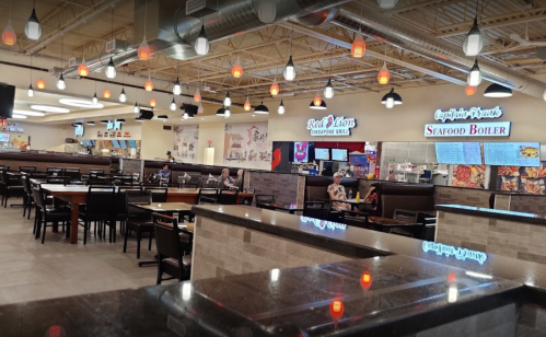 A spacious restaurant interior with tables, pendant lights, and seafood-themed signage. Customers are dining.