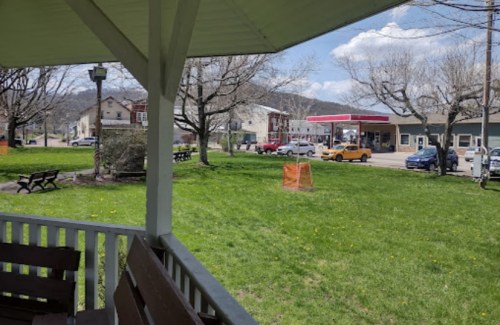 A view from a gazebo overlooking a grassy area with benches, buildings, and a gas station in the background.