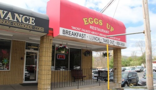 A restaurant called "Eggs Up" with a red awning, offering breakfast, lunch, and takeout, with an "Open" sign visible.