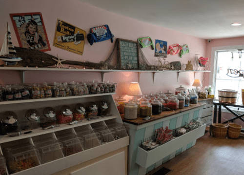 A colorful candy shop interior with jars of sweets on shelves and vintage decor on the walls.