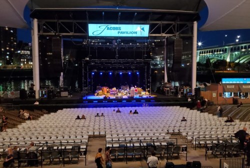 Empty concert venue at night, featuring a stage with lights and rows of seats under a large canopy.