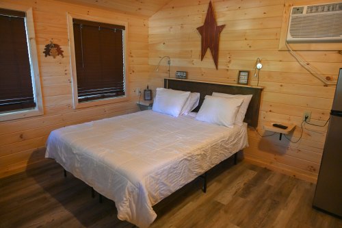 Cozy wooden room featuring a double bed, star decor, and air conditioning unit. Warm, inviting atmosphere.