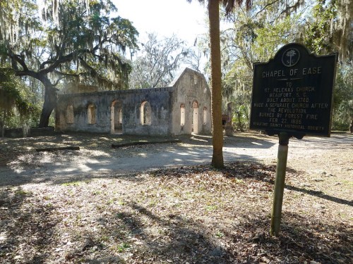 Ruins of the Chapel of Ease, a historic site with a sign detailing its history, surrounded by trees and Spanish moss.