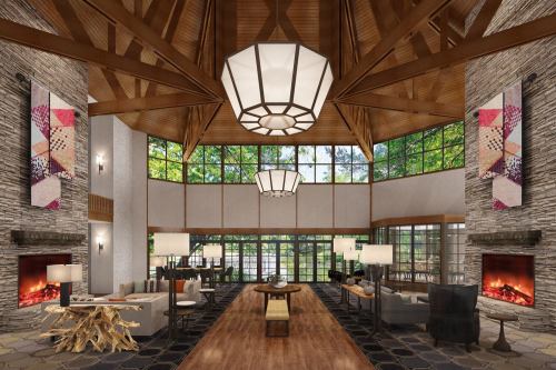 A spacious lodge interior with high wooden ceilings, large windows, and cozy seating areas by stone fireplaces.