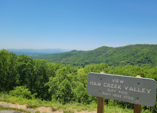 Scenic view of Haw Creek Valley with lush green hills under a clear blue sky, featuring an elevation sign.