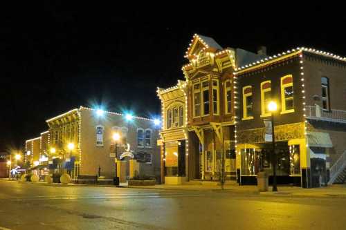 A charming street at night, featuring historic buildings adorned with festive lights and glowing street lamps.