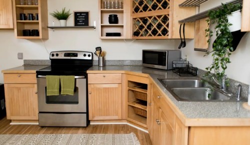 A modern kitchen with wooden cabinets, stainless steel appliances, and a countertop with a sink and baskets.