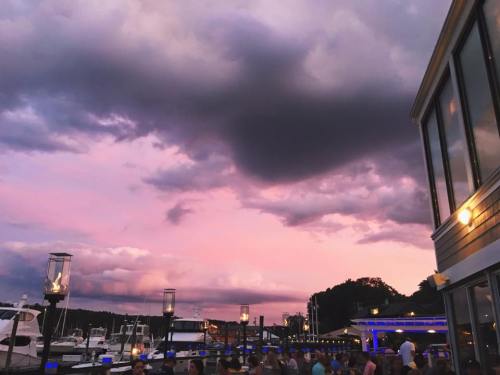 A scenic view of a marina at sunset, with dramatic clouds and a colorful sky reflecting over the water.