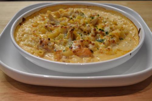 Creamy baked macaroni and cheese with chunks of chicken, topped with a golden crust and sprinkled with herbs.