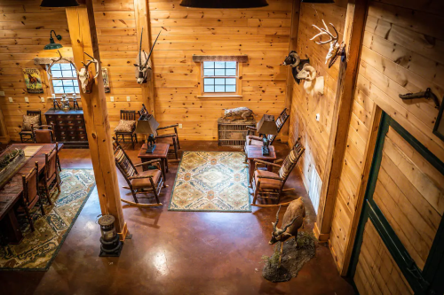 Cozy wooden interior with rustic furniture, a large table, and mounted animal heads on the walls.