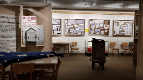 A museum interior featuring display boards, a cart, and a table with a folded flag.