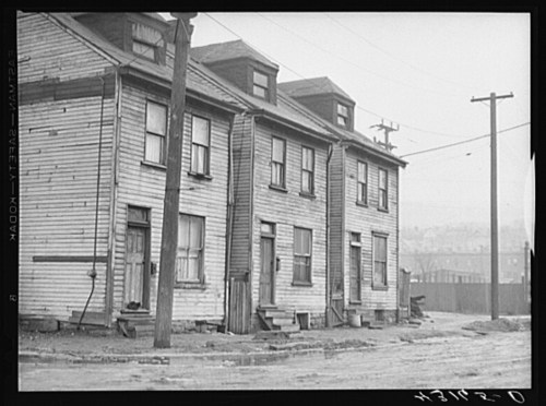 A row of weathered wooden houses with power lines, set on a foggy street.