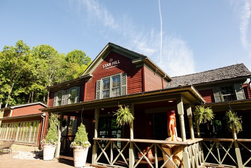 A red wooden building with "Star Hill" sign, surrounded by greenery and a clear blue sky.