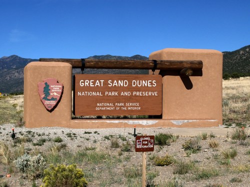 Sign for Great Sand Dunes National Park and Preserve, featuring a rustic design and surrounding natural landscape.
