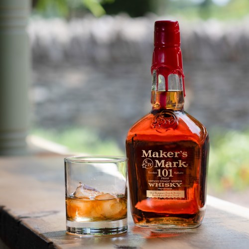A bottle of Maker's Mark 101 whisky next to a glass filled with ice and a pour of the drink.