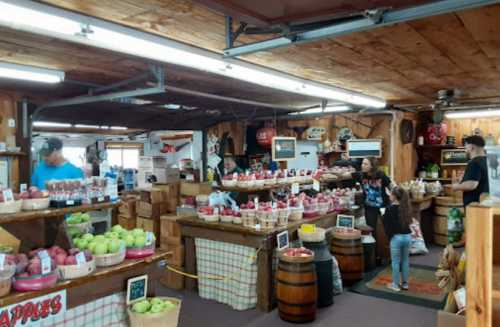 A bustling market interior with wooden shelves filled with baskets of apples and customers browsing.