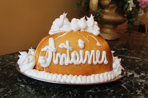 A dome-shaped cake decorated with white frosting and the word "Intainer" written on top.