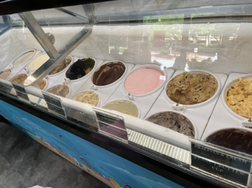 A display case filled with various flavors of ice cream in tubs, showcasing a colorful assortment.
