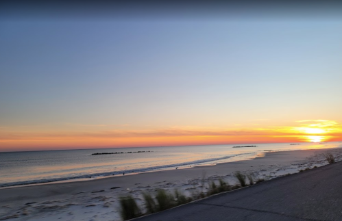 A serene beach at sunset, with gentle waves and a colorful sky reflecting orange and pink hues.