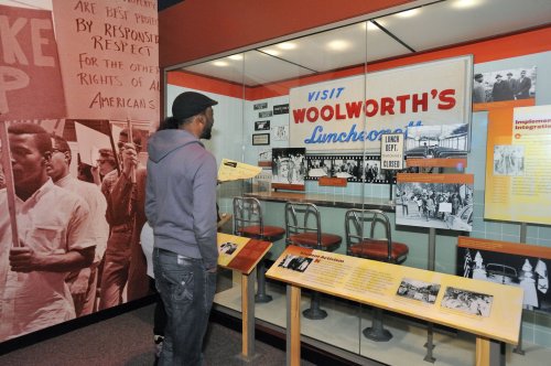 A visitor observes a display about Woolworth's lunch counter, featuring historical photos and artifacts from the civil rights movement.