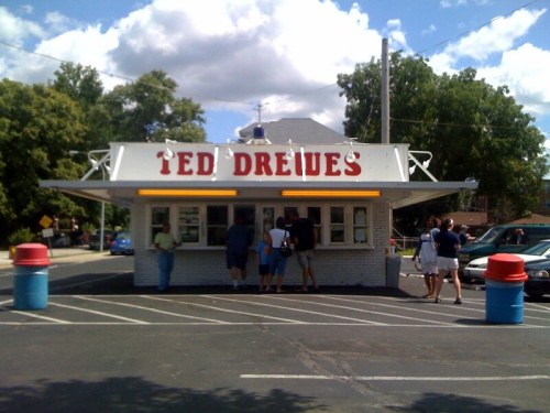 A small, retro-style food stand with "Ted Drewes" sign, people lined up outside on a sunny day.