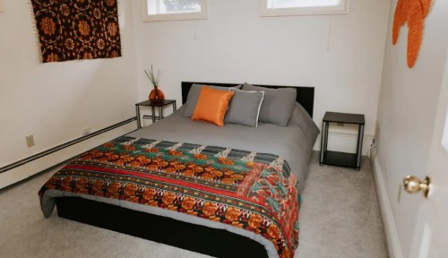 Cozy bedroom featuring a bed with a colorful blanket, two nightstands, and decorative wall art.