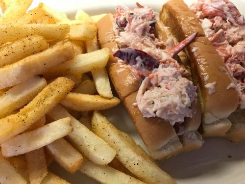 Two lobster rolls filled with lobster salad, served with a side of golden French fries.