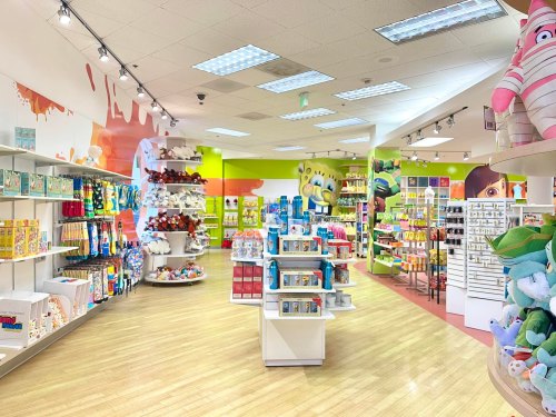 Brightly colored store interior featuring shelves of toys, plushies, and various merchandise in a playful layout.