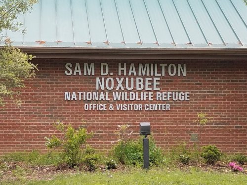 Sign for Sam D. Hamilton Noxubee National Wildlife Refuge Office & Visitor Center, featuring brick and green roof.