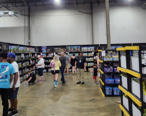 A busy store aisle filled with shelves of toys and games, with people browsing and shopping.