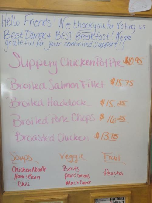 Menu board listing daily specials: Slippery Chicken Pot Pie, Broiled Salmon, Haddock, Pork Chops, Broasted Chicken, and sides.