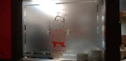 Frosted glass window featuring a cartoon chef holding a spoon and food, with the words "fresh unique delicious."