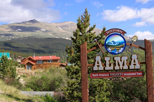 Sign for historic Alma, North America's highest incorporated town, with mountains and trees in the background.