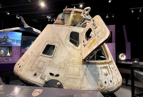 A vintage spacecraft on display in a museum, showcasing its metallic exterior and open hatch.