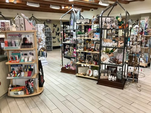 A bright gift shop interior filled with various decorative items, shelves, and displays showcasing unique products.