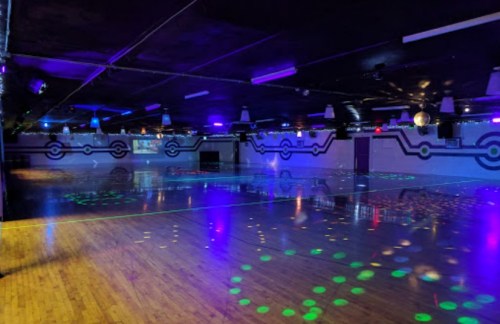 A spacious roller skating rink with colorful lights and a polished wooden floor, ready for skating.
