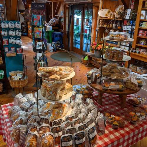 A cozy shop interior with baked goods displayed on tables, a checkered tablecloth, and a welcoming entrance.