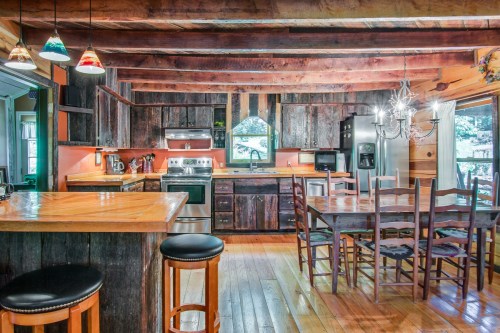 Cozy rustic kitchen with wooden beams, modern appliances, and a dining table, featuring warm lighting and a welcoming atmosphere.
