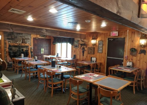 Cozy restaurant interior with wooden walls, tables set for dining, and a warm, inviting atmosphere.