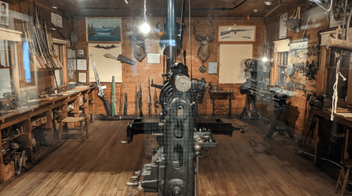 A vintage workshop filled with tools, machinery, and mounted animal heads on the walls.