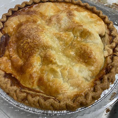 A freshly baked pie with a golden-brown crust, slightly puffed and glistening, in a silver pie dish.