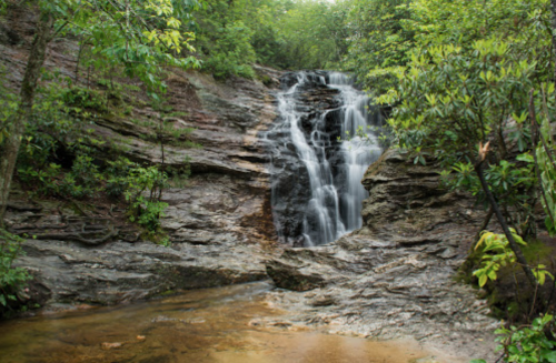 A serene waterfall cascading over rocky terrain, surrounded by lush green foliage and trees.