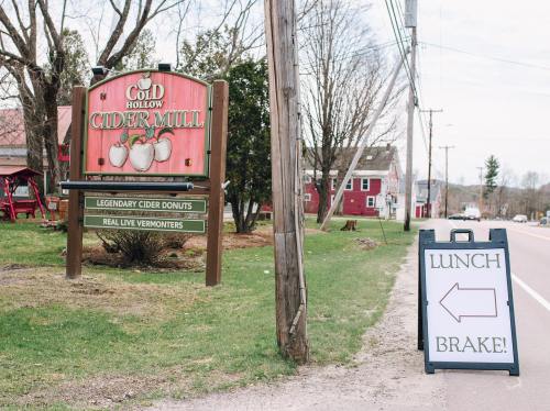 Sign for Cold Hollow Cider Mill featuring cider donuts, with a sandwich board indicating "Lunch Brake!" and an arrow left.